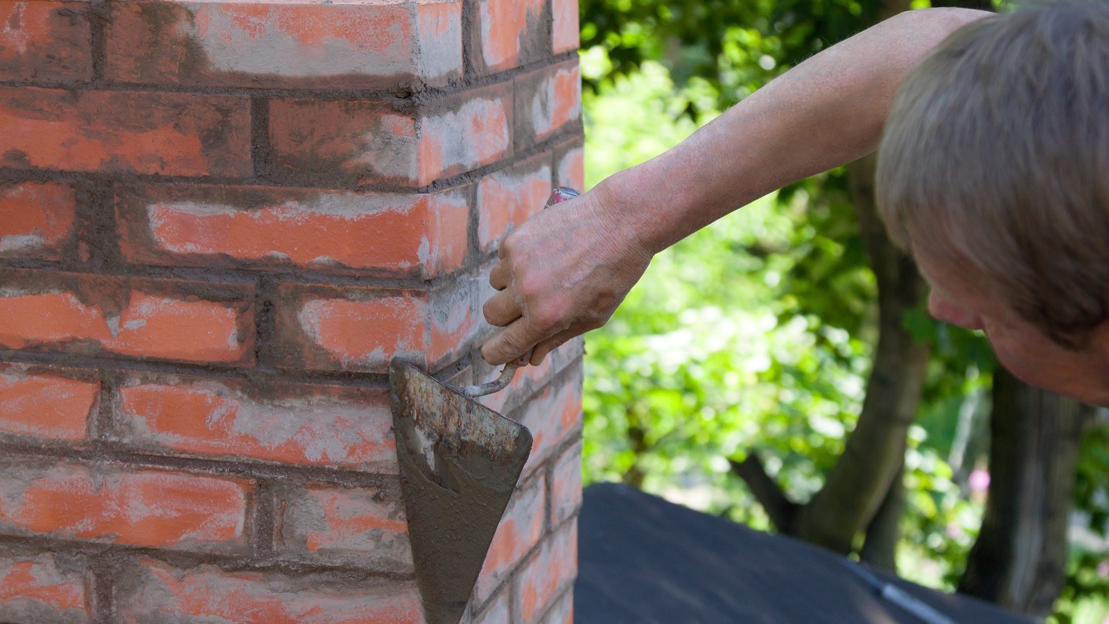 Masonry contractors repointing a brick rowhouse facade in Baltimore, MD
