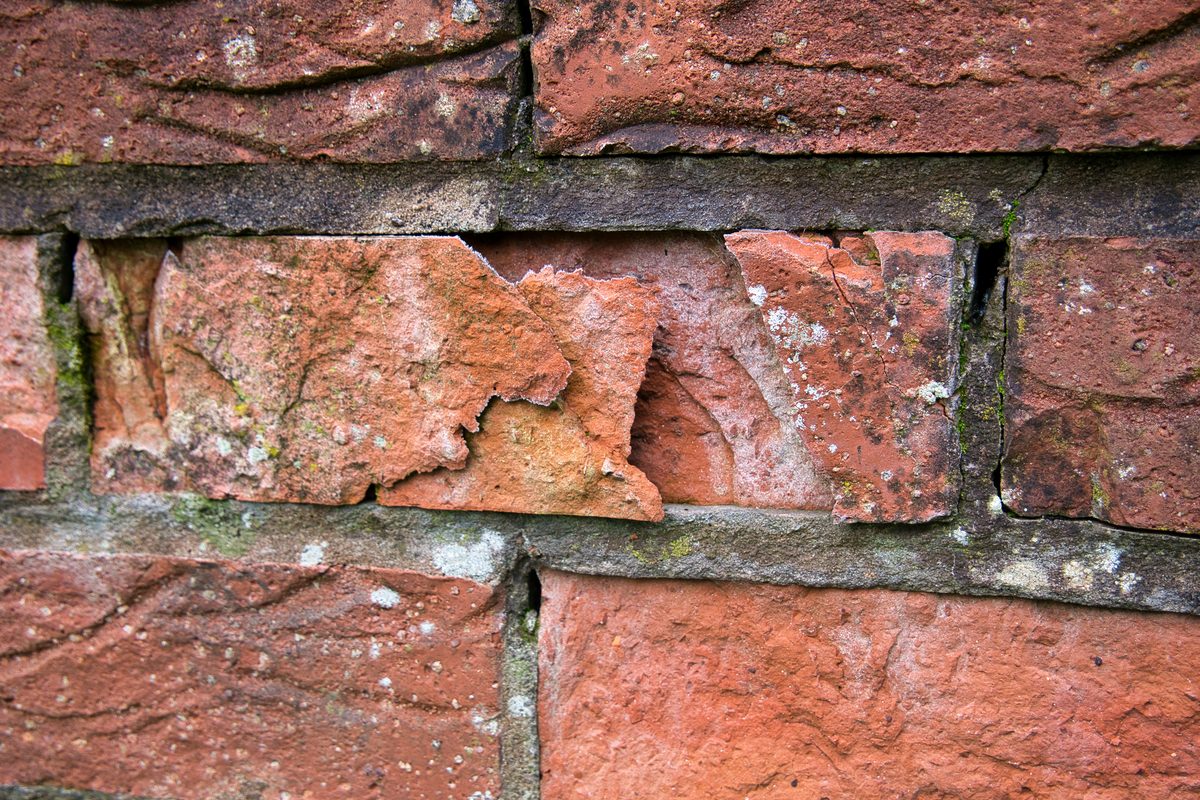 Spalled brick face caused by trapped moisture behind hard mortar