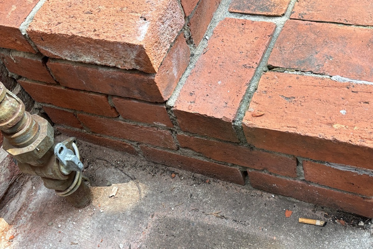 Spalled brick faces beside hard cement joints from an incorrect repointing mix